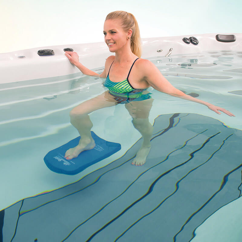 Woman working out in a swim spa with kick board